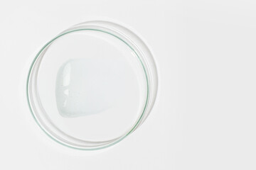 Petri dish on a light background. With a smear of clear gel. Cosmetic gel, lubricant, gel. View...