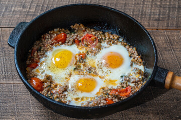 Boiled buckwheat with fried eggs, red peppers, tomato and onions, closeup, Ukraine. Food background. Healthy food