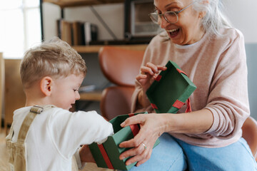 Grandmother giving gift to her little grandson.