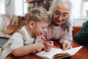 Grandmother drawing in a notepad with her little grandson.