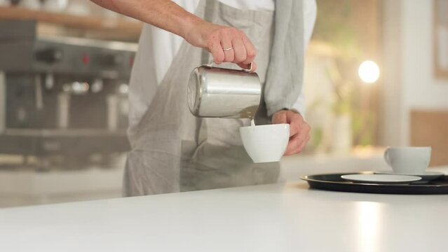 Barista, milk and coffee cup with man and hands, drink preparation with latte art and countertop in cafe. Process, pour with jug and premium blend caffeine, male work in restaurant and hot beverage