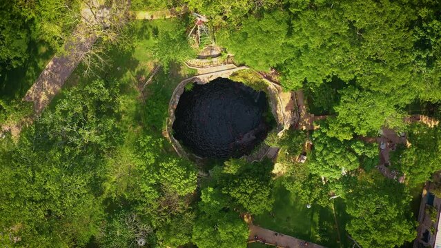 Aerial view of cenote Saamal in Valladolid, Mexico. People rest and swim in cenote. 
A small waterfall in a cenote.