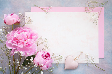 Decorative colorful background with pink flowers peonies, gypsophila and paper for text holiday greetings