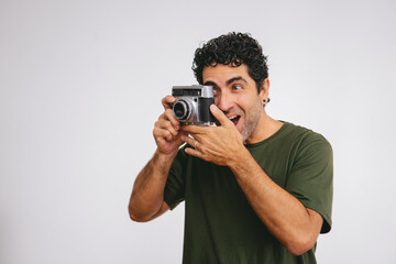 Middle-aged Latin man caught using an antique roll camera on a white background. Copy space.