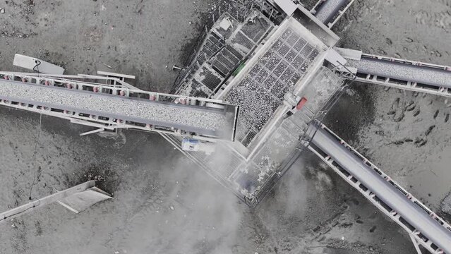Gravel poured from conveyor with dust cloud at mining quarry upper view. Automatic technology of mineral deposits processing