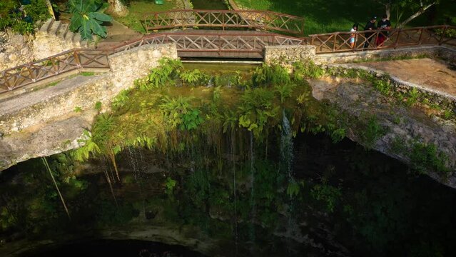Aerial view of cenote Saamal in Valladolid, Mexico. People rest and swim in cenote. 
A small waterfall in a cenote.