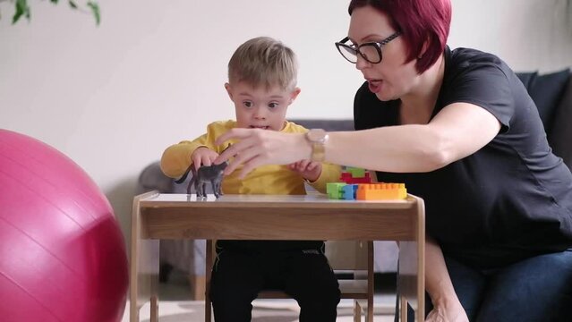 playful child with Down syndrome exploring creativity and learning with colorful animal toys and geometric shapes, supported by mother in a relaxed and enjoyable activity at home