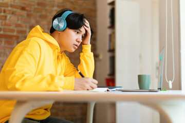 Korean Teenager Boy At Laptop Learning Online Wearing Earphones Indoor