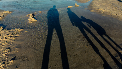 Shadow of family of father, son and daughter during sunset over Baltic Sea, Poland