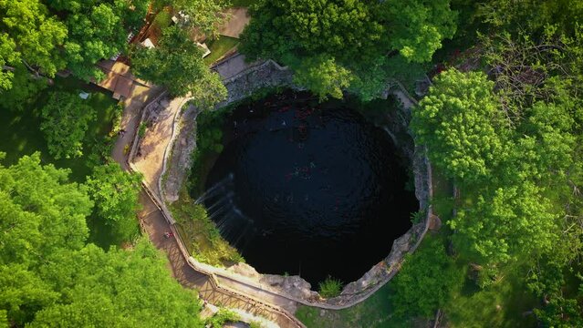 Aerial view of cenote Saamal in Valladolid, Mexico. People rest and swim in cenote. 
A small waterfall in a cenote.