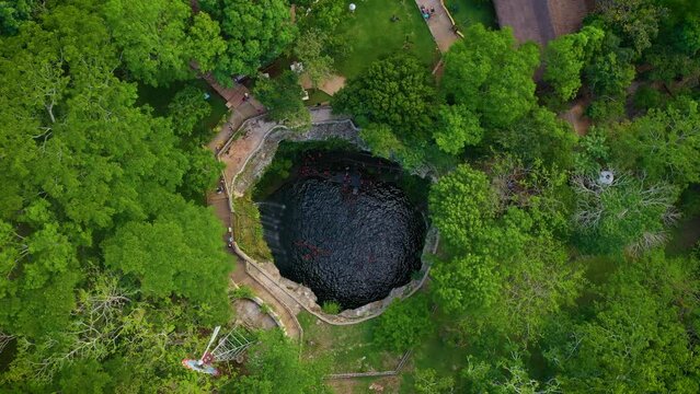 Aerial view of cenote Saamal in Valladolid, Mexico. People rest and swim in cenote. 
A small waterfall in a cenote.