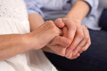 An adult woman holding an elderly mother-grandmother by the hands.