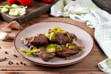 Rare roasted thick juicy beef fillet medallion topped with leek on wooden table