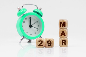 On a white background, a green alarm clock and a calendar with the inscription - March 29
