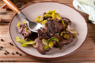 Rare roasted thick juicy beef fillet medallion topped with leek on wooden table