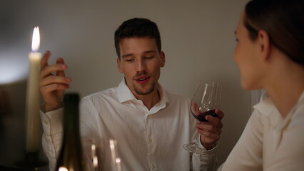 Cheerful man treating wife candles dinner close up. Relaxed lovers flirting