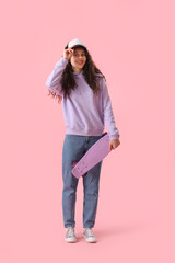 Teenage girl in cap with skateboard on pink background