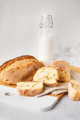 Board with slices of fresh bread on white table