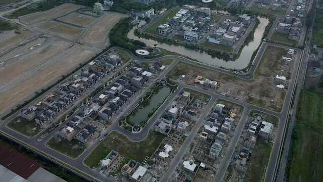 Aerial footage of a residential complex that are under construction, focused on a small pond in the middle