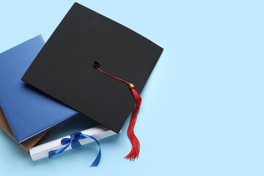 Diploma with ribbon, graduation hat and books on blue background