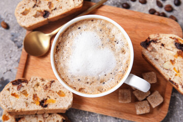 Board with delicious biscotti cookies and cup of coffee on grey grunge background
