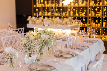 Served wedding table with decorative fresh white flowers and candles. Celebration details. Hanging flower beds and light bulbs Wedding decoration and decor, floristic concept
