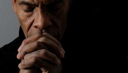 man praying to god with hands together Caribbean man praying with black background stock photos stock photo	