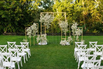 Wedding ceremony outdoor. A beautiful and stylish golden wedding arch, decorated by fresh white...