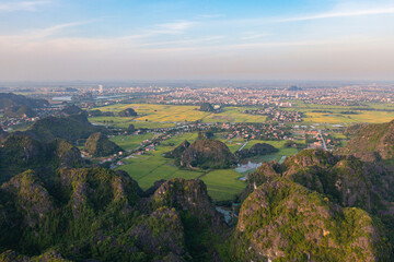 Fototapeta na wymiar Aerial top view of fresh paddy rice, green agricultural fields with mountain hills valley in countryside or rural area of Ninh Binh, in Asia, Vietnam. Nature landscape background.