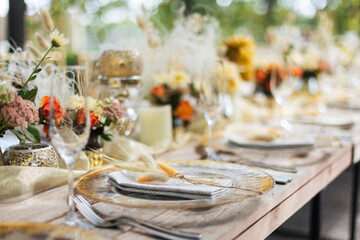 Wedding decorations. Served wedding table with golden plates, napkins, decorative fresh and dried flowers, candles and and light bulbs. Celebration details, wedding outdoor	

