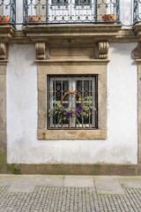 Wreath with flowers on a window in an old stucco building.