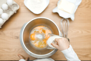 Kid's hands sprinkling sugar. Eggs, butter, flour. Cooking ingredients in bowl, ready for mixing dough. Cookbook