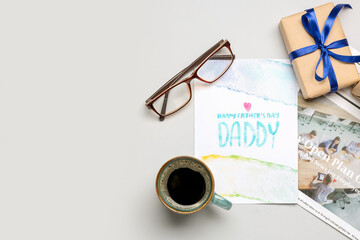 Composition with greeting card, newspaper, eyeglasses, cup of coffee and gift for Father's Day celebration on white background