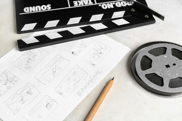 Movie clapper with storyboard and film reel on light background, closeup