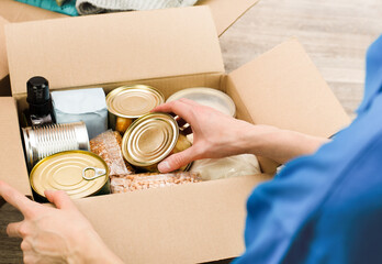 a woman puts groceries in a cardboard box with humanitarian aid, close-up