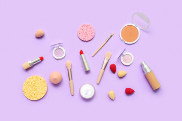 Naklejka premium Decorative cosmetics with makeup brushes and sponges on lilac background