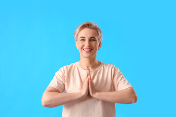 Mature woman meditating on light blue background