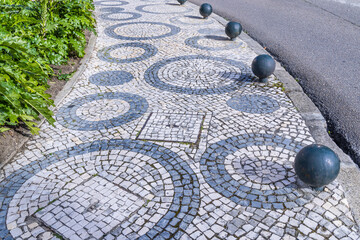 Circles in a sidewalk made of black and white cobblestones.