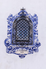 Traditional hand painted azulejos decorative tiles frame a window in a building in Aveiro.