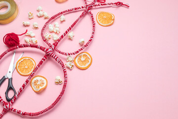 Flatly Survakane, Survachka On Pink Background. Bulgarian Traditional Cornel Stick With Decorations, Dried Fruits, Threads, Popcorn. Christmas Entertainment. Copy space For text, Horizontal Plane