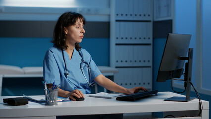 Tired stressed medical nurse standing at desk working over hours at health care treatment typing patient prescription during checkup visit appointment. Exhausted assistant analyzing disease diagnosis - obrazy, fototapety, plakaty