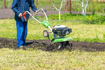 Farmer man plows the land with a cultivator preparing the soil for sowing