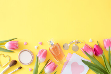 Happy Mommy Day concept. Flat lay photo of colorful tulips perfume bottle cosmetics brushes bijouterie earrings and postcard with colorful hearts on light yellow background with copyspace