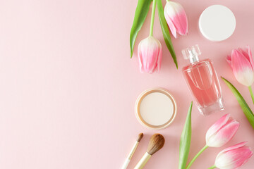 Obraz na płótnie Canvas Flat lay composition of colorful tulips perfume bottle cosmetics brushes makeup powder and cream jar on isolated pastel pink background with empty space. Mother's Day mood concept.