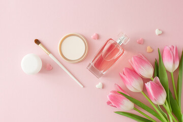 Top view composition of bunch of pink tulips perfume bottle cosmetic brush makeup powder cream jar and colorful hearts on isolated pastel pink background. Mother's Day atmosphere concept.
