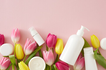 Obraz na płótnie Canvas Organic skin care concept. Top view photo of pump bottle without label cosmetic tubes cream jars and colorful tulips on isolated pastel pink background with copyspace