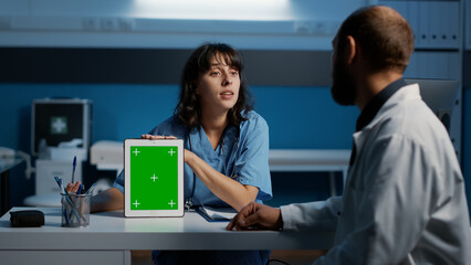 Medical assistant holding device pointing at green screen display while discussing patient...