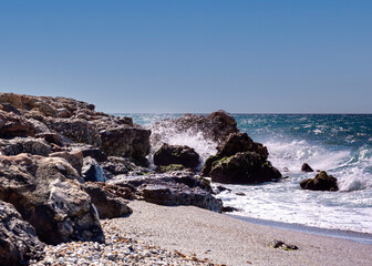 Wellen brechen sich am Felsen bei blauem Himmel.jpg