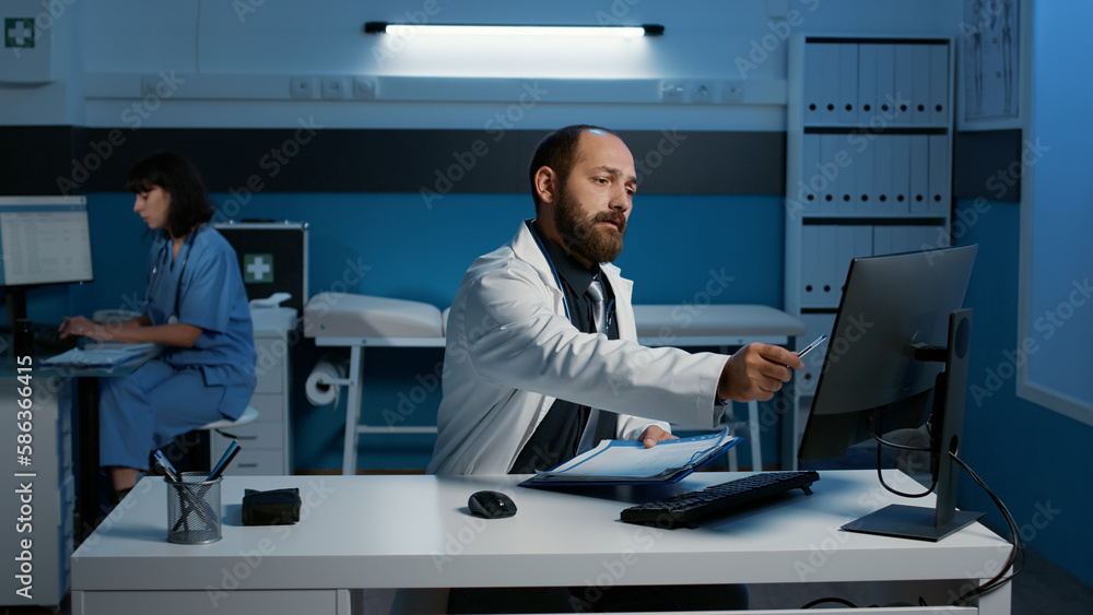 Poster practitioner doctor standing at desk looking at data expertise on computer comparing with medical pa