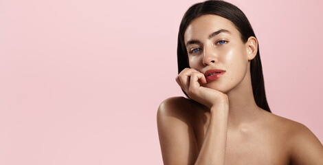 Beauty face and spa. Woman with perfect body, clean nourished skin, biting lip and look aside. Girl model using antiaging cosmetics and vitamin c serum for bettet smoother skin tone, pink background